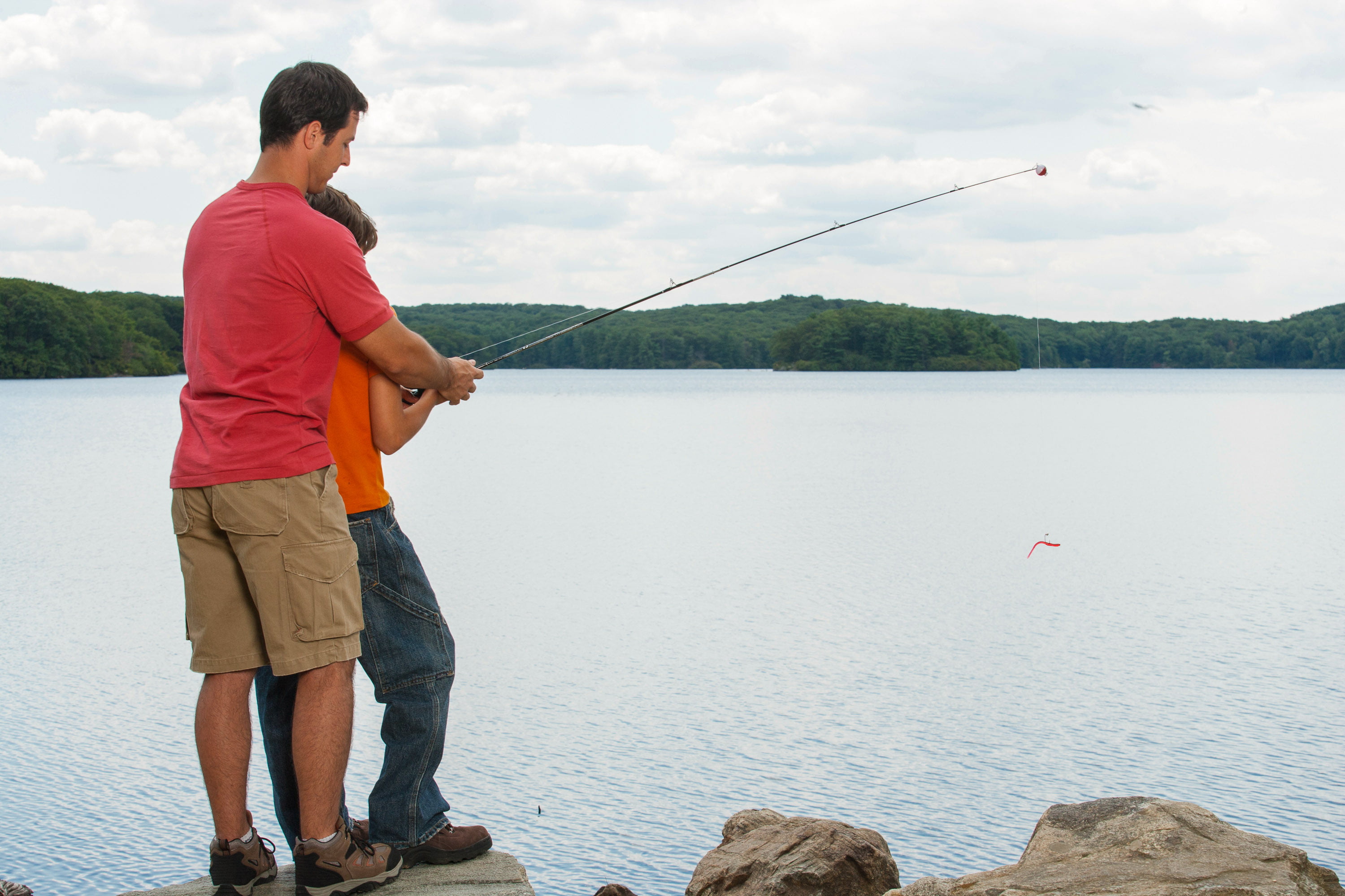 Father and son fishing at lake together