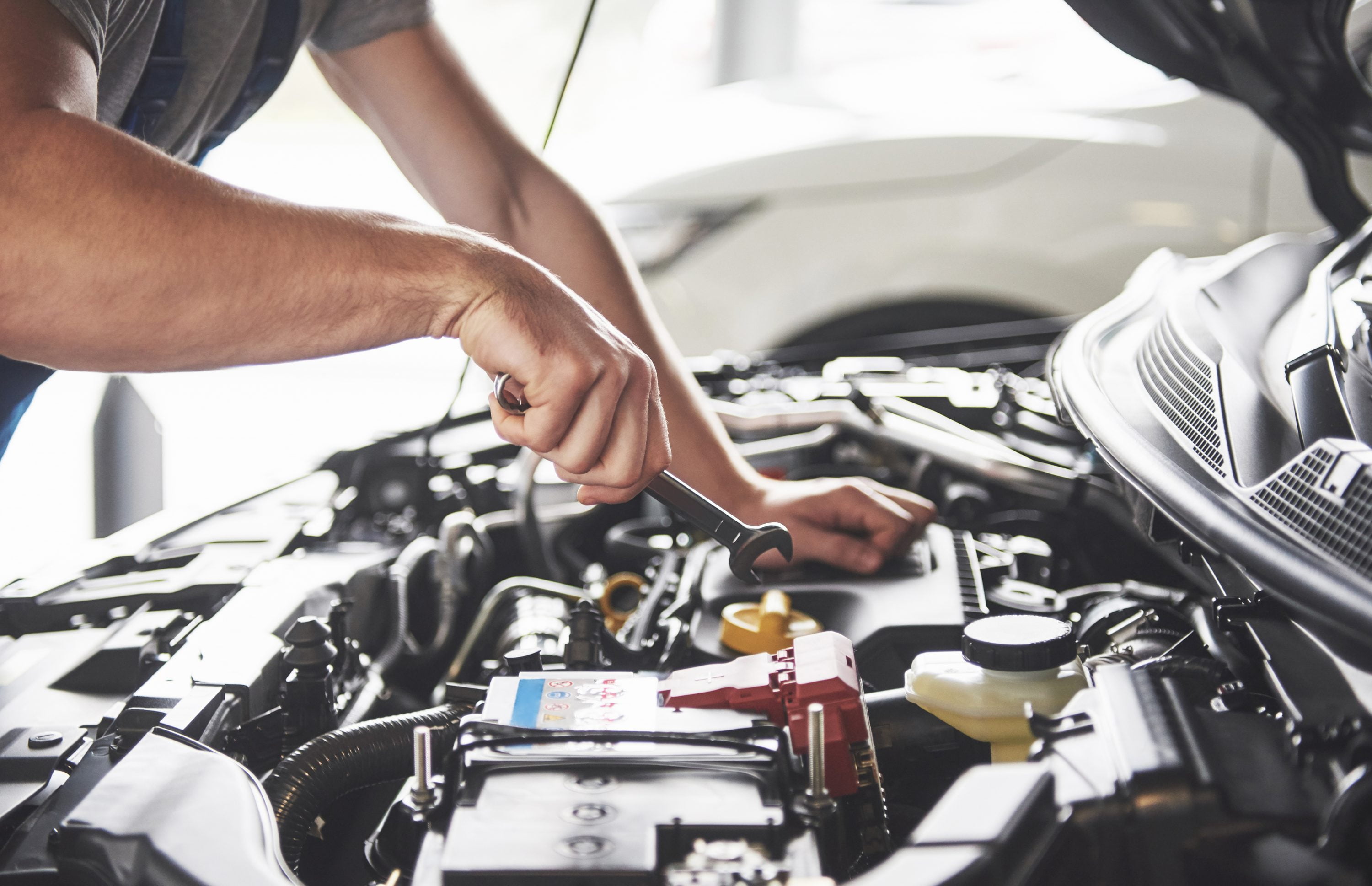 Picture showing muscular car service worker repairing vehicle.