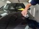 The process of applying a nano-ceramic coating on the car's hood by a male worker with a sponge and special chemical composition to protect the paint on the body from scratches, chips and damage.