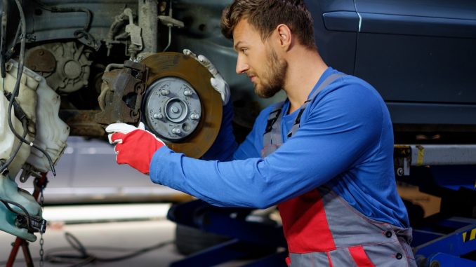 Mechanic checking car brake system in a workshop