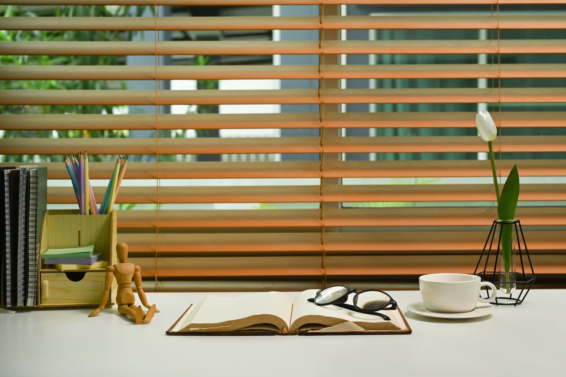 Home office desk with eyeglasses, books, coffee cup and supplies.
